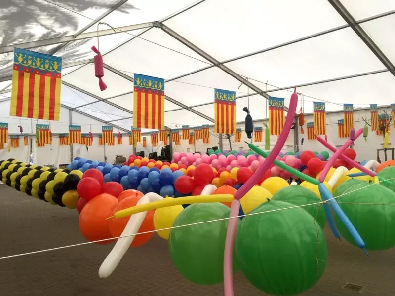 Carpa de fiestas decorada con banderas valencianas y guirnaldas de globos de colores
