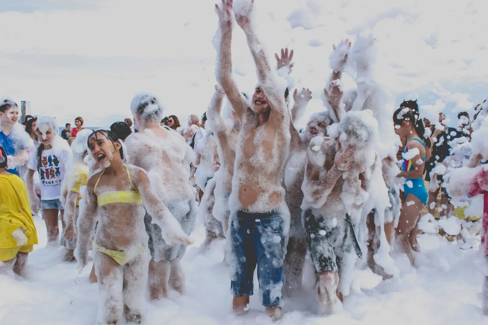 Grupo de jóvenes cubiertos de espuma, con los brazos en alto, en una fiesta de la espuma