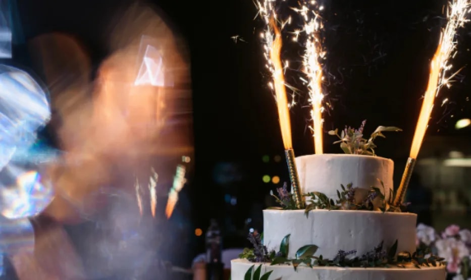 Tarta de boda de dos pisos con bengalas encendidas, de noche