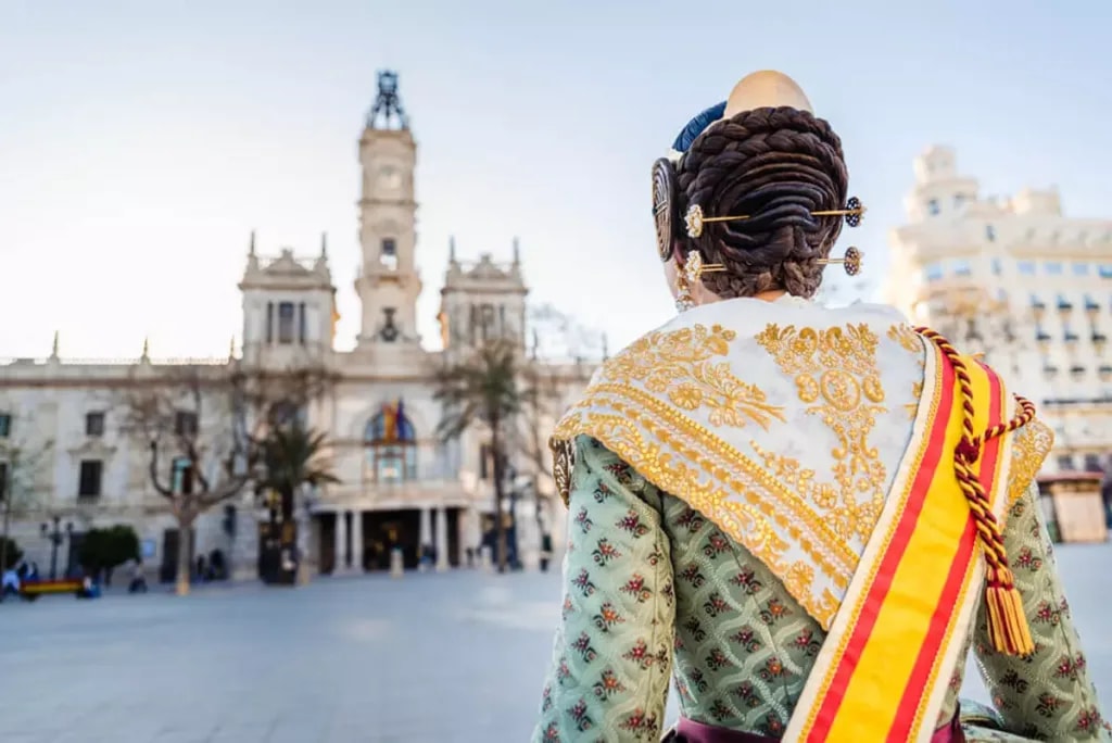 Una fallera de espaldas, con el peinado tradicional, frente al ayuntamiento de Valencia