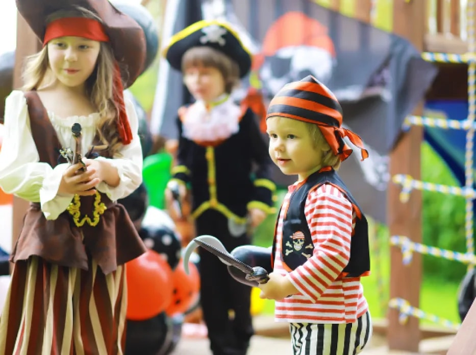 Tres niños disfrazados de piratas jugando en un parque infantil