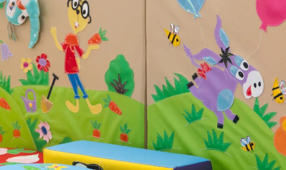 Sala de juegos infantil con paneles pintados de animales y módulos blandos de colores
